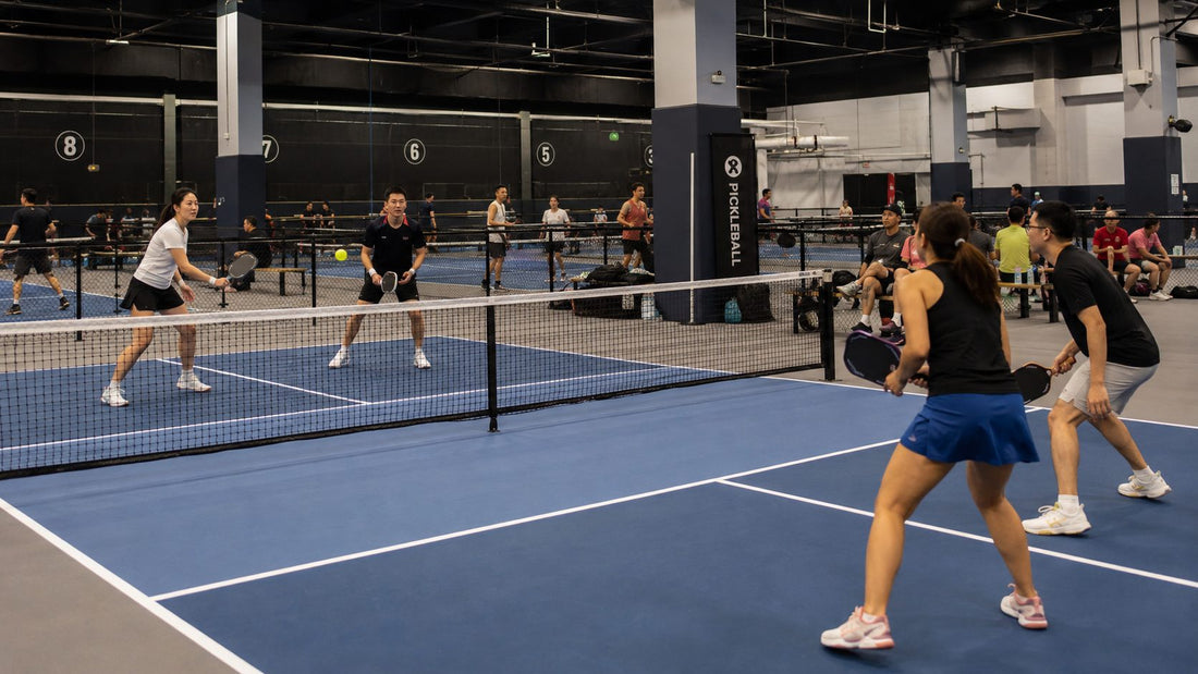Two pairs playing mixed doubles pickleball on an indoor court in Singapore
