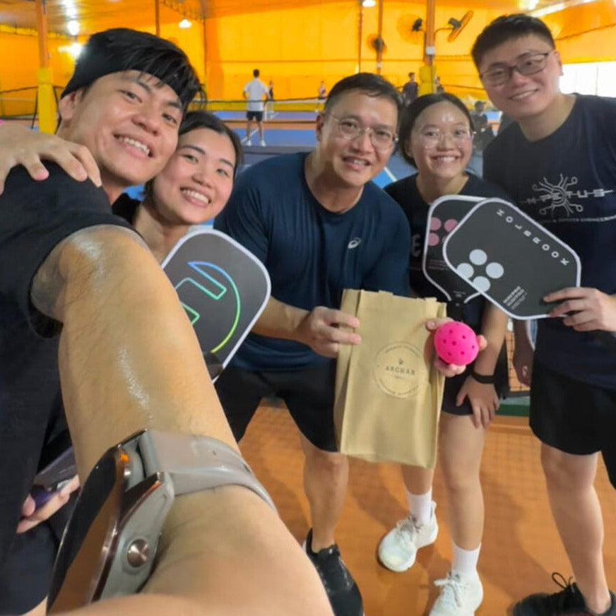 Group of people posing with paddle sports equipment on a court